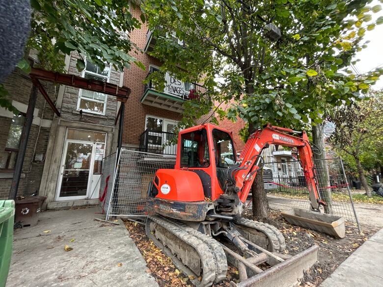 A small bulldozer in front of an apartment building. 