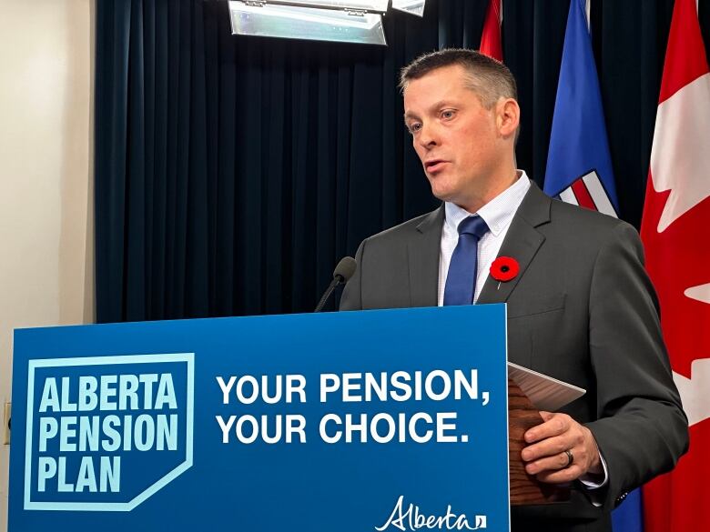 A man in a suit stands at a podium with 