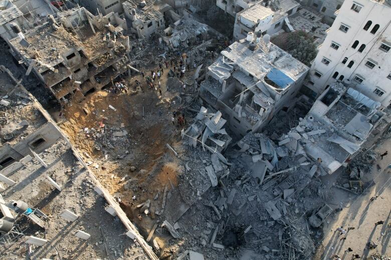 An overhead shot displays destroyed buildings and concrete debris on the ground.