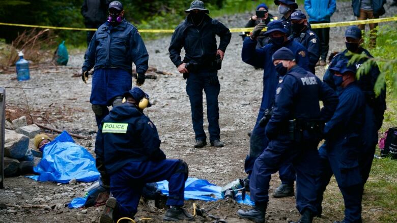 RCMP officers surround a protester cemented into the ground during a protest in Fairy Creek using a technique called a Sleeping Dragon