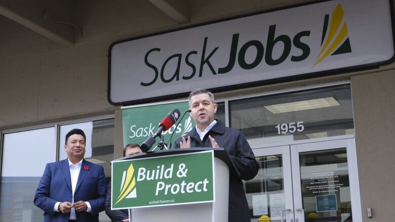 Jeremy Harrison stand behind a podium while speaking into a microphone and motioning with his hands