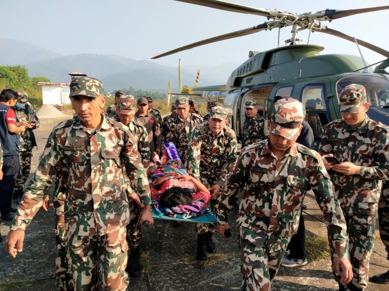 Army personnel carry an injured person on a stretcher after an earthquake in Nepal caused extensive damage.