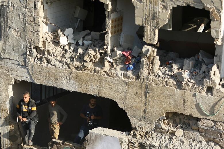 People gather Saturday at the site of a residential building in Khan Younis in the Gaza Strip, which was hit by Israeli airstrikes.