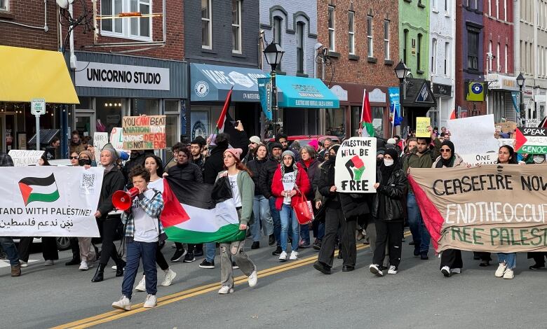 People carrying protest signs and flags march down a city street.