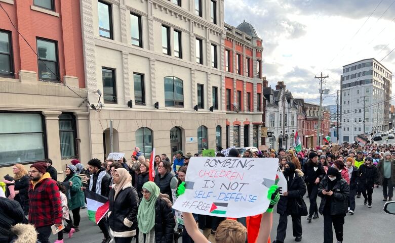 Protesters march down a street in winter clothes.