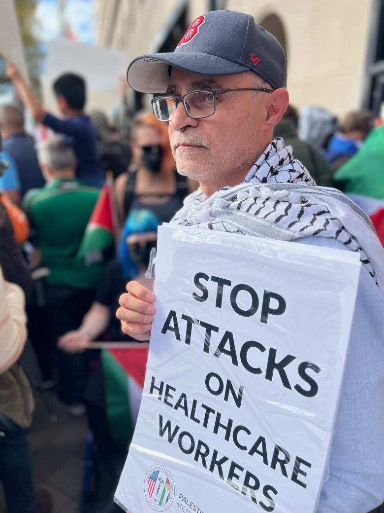 Man in Red Sox cap holds up sign that says: Stop attacks on healthcare workers