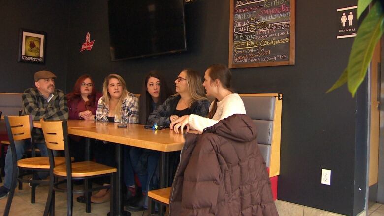 A group of people holds a meeting around a table at a restaurant.