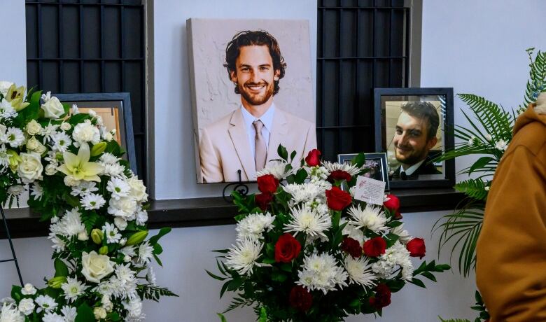 Images of a man are hung next to flowers.