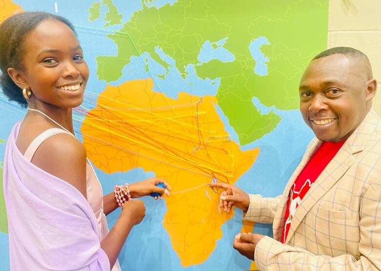 Two people use string to map their journey on a map that highlights East Africa.