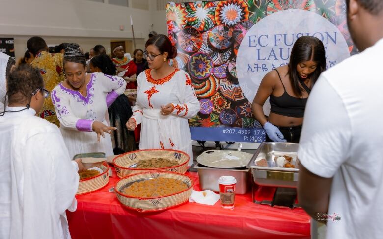 Women serve food arranged on platters. 