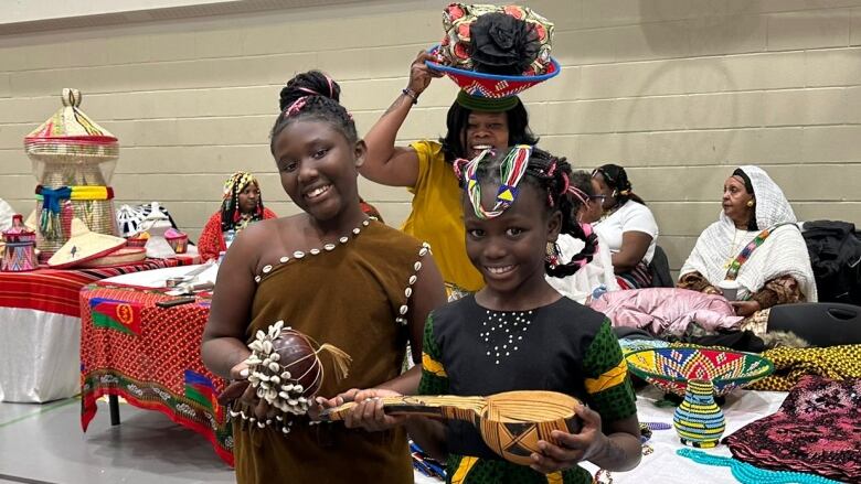 Two young girls smile at the camera wearing decorated clothing. 