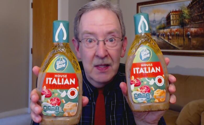  Edgar Dworsky holds up two bottles of the same version of salad dressing. 