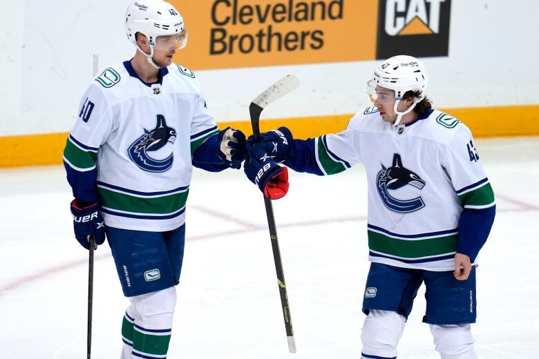 Two hockey players bump fists on the ice.