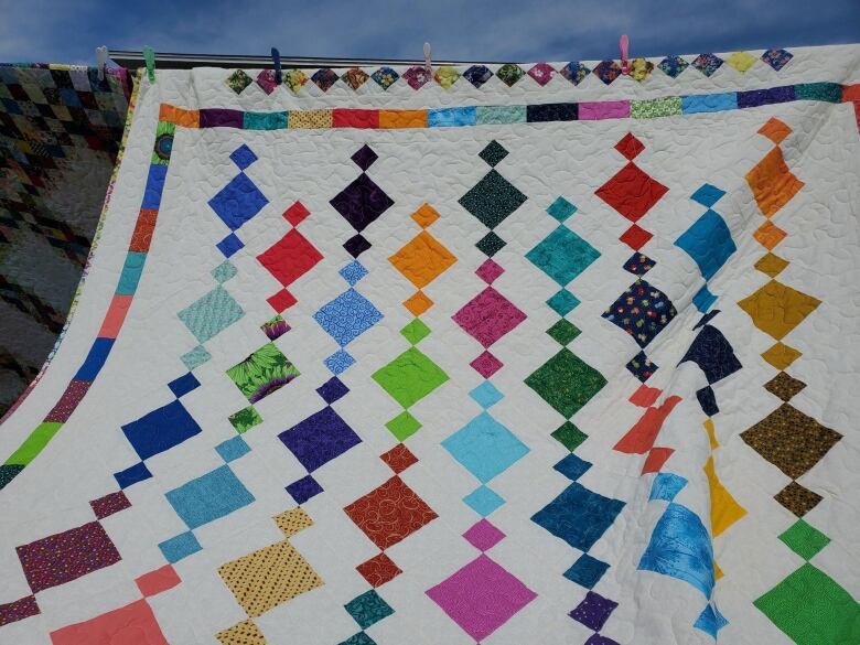 A quilt with vibant colours and columns of geometric designs. 