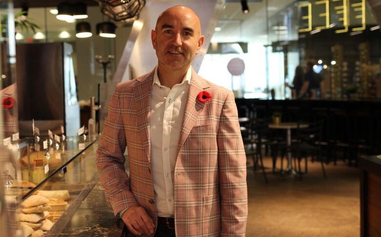 A man in a pink checkered jacket and white button down poses for a photo inside a quick service restaurant in downtown Calgary.