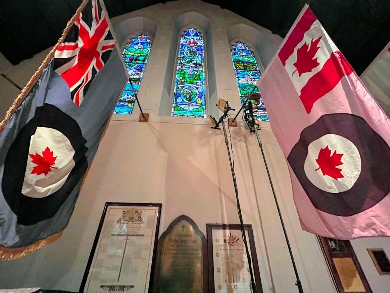 Military flags hang below stained glass windows.