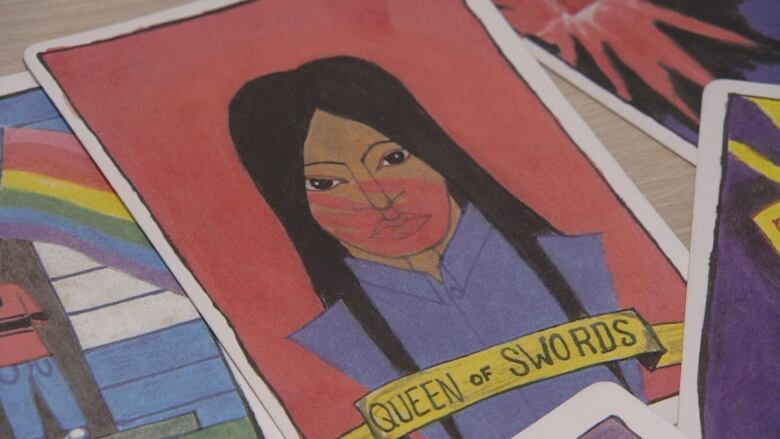 A illustration of the Queen of Swords tarot card with an Indigenous woman with long hair and a red handprint over her face. 