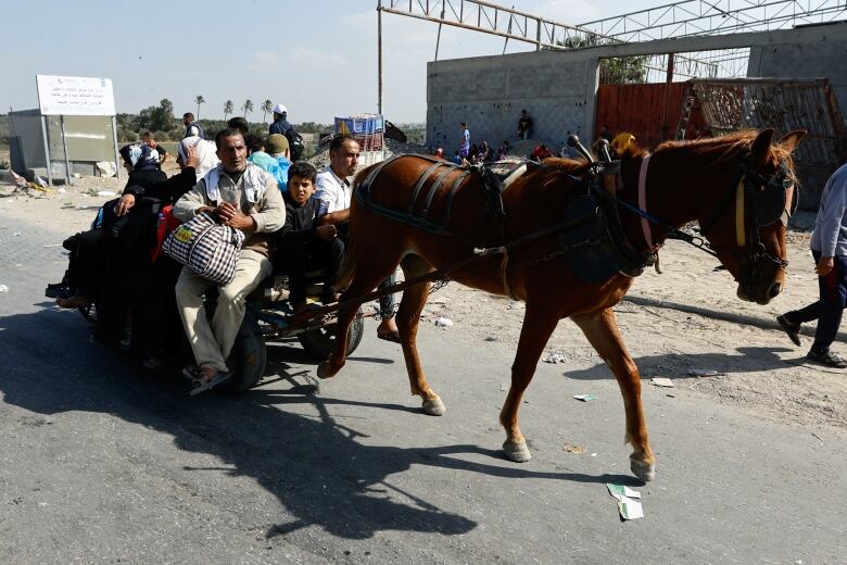 People are seen riding on a cart, as they try to get out of the northern Gaza Strip on Friday.