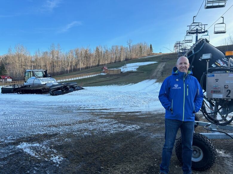 A man standing beside a snowmaking machine. 