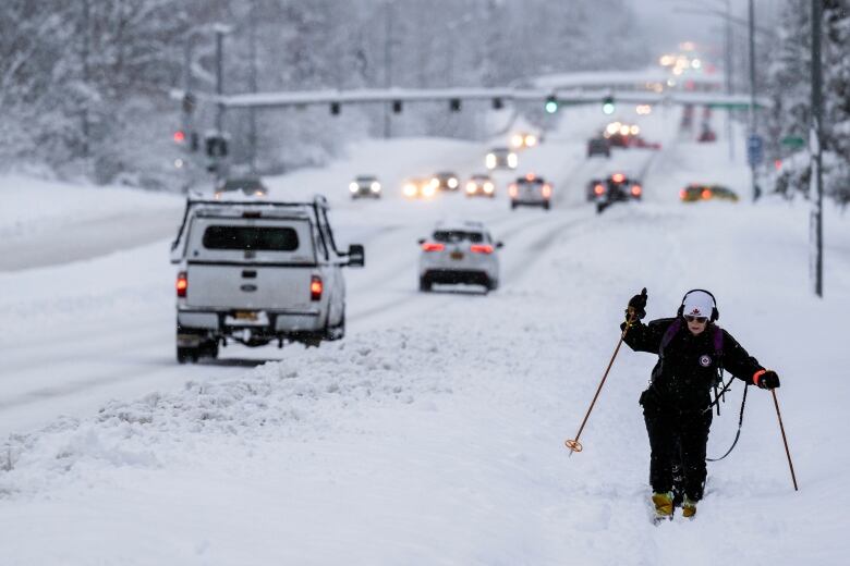 A person cross-country skis alongside a snowy highway.