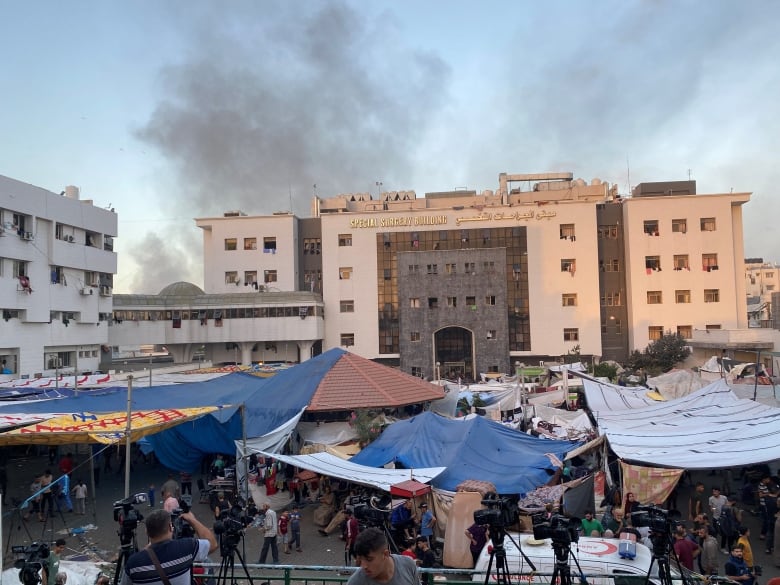 People in the forefront take shelter outside Al-Shifa hospital in Gaza.