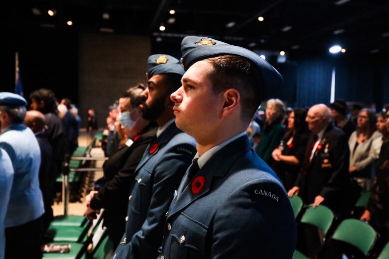 People wearing uniforms sits in rows in a crowd.