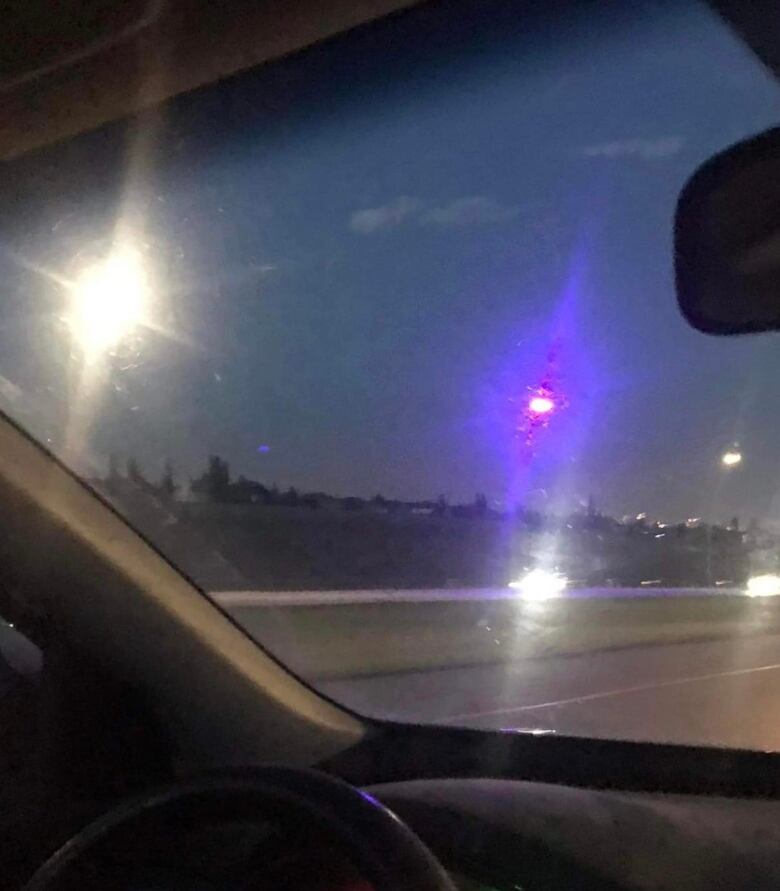 A purple street light on a freeway in Calgary, captured from inside of a car.