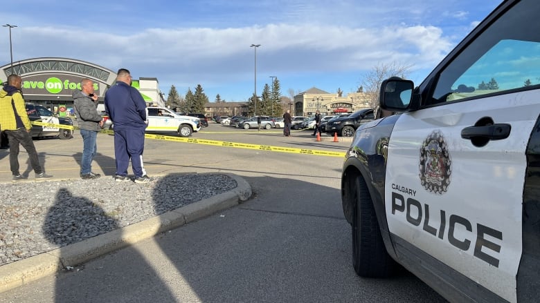 A police car is parked in a parking lot that is lined by police tape.