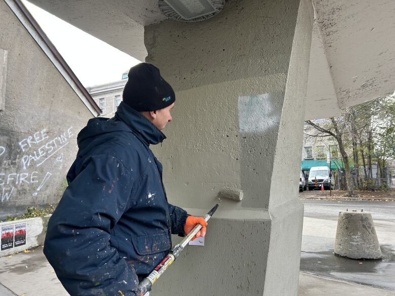 An STM worker covers up graffiti with a paint roller. 