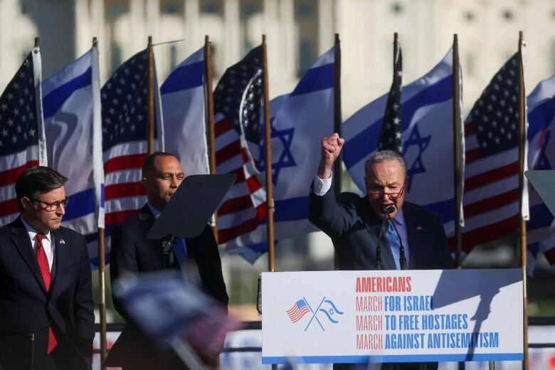 Chuck Schumer raises fist while speaking outdoors