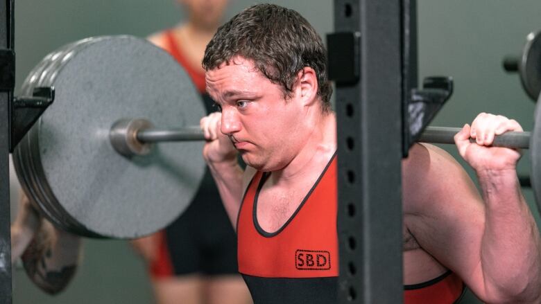 A man lifts a weight in a gym.