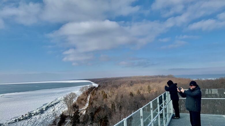 Two people take pictures from the top of the Point Pelee observation tower during the wintertime when it was open.