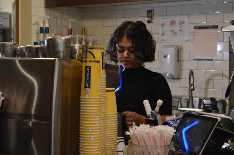 Woman makes coffee behind counter