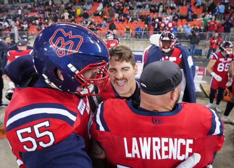 Three football players dressed in red and blue uniforms rejoice,