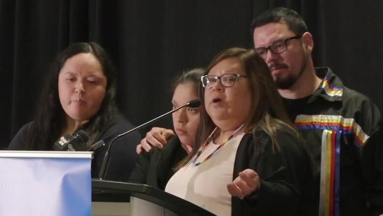 A family, which includes two daughters, a mother and a father, is pictured standing at a podium.