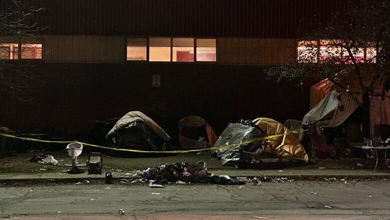 Tents behind police tape at night.