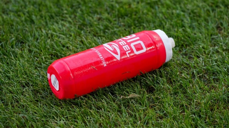 A Biosteel bottle is shown on some artificial turf on a soccer field.