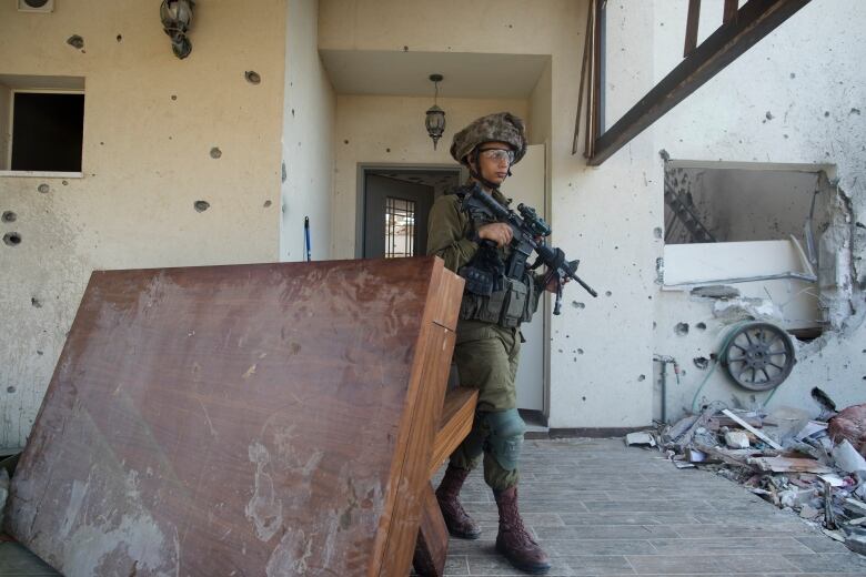 An Israeli soldier inspects a home in Be'eri, Israeli, which was destroyed during a battle between Hamas militants and Israeli soldiers.