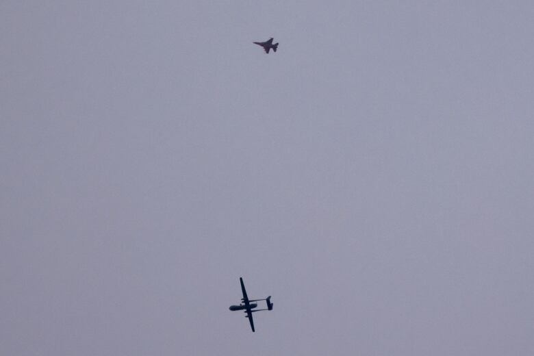 A drone and a fighter jet are seen above the ground on a stretch of the southern Israeli border near the Gaza Strip.