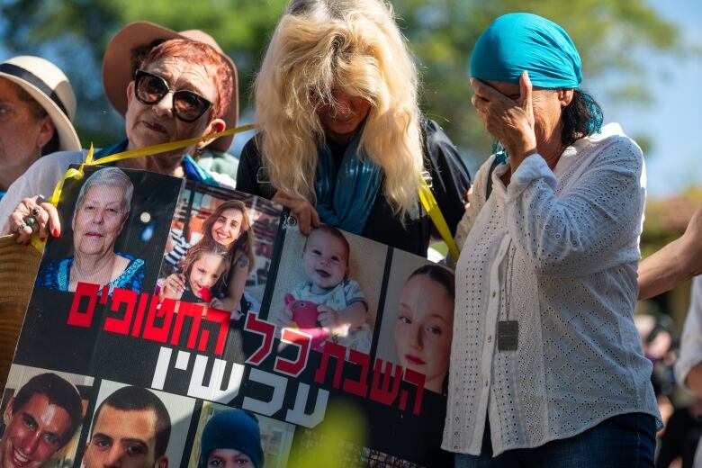 Three women hold each other while crying at a memorial services in Israel.