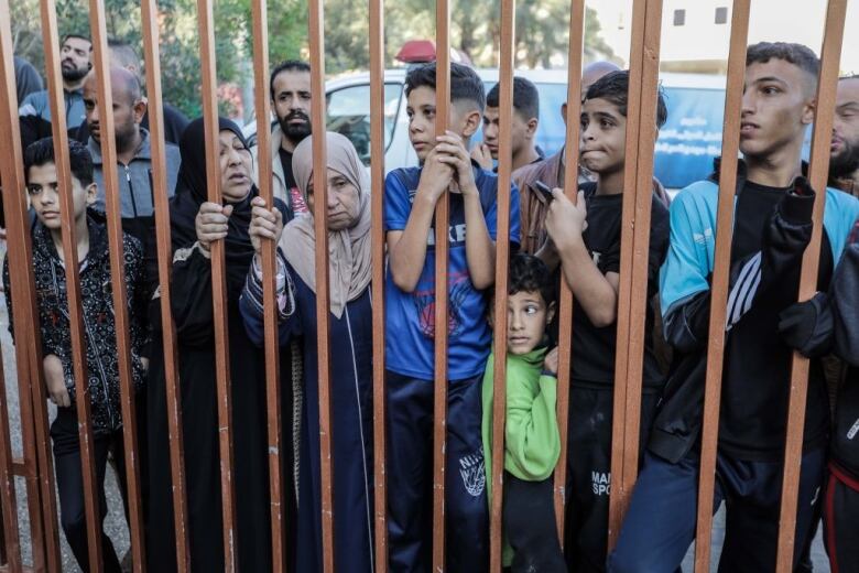 People gather behind a fence.