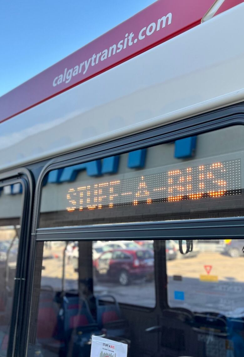 A city transit bus displays a sign that says 'Stuff-a-bus.'