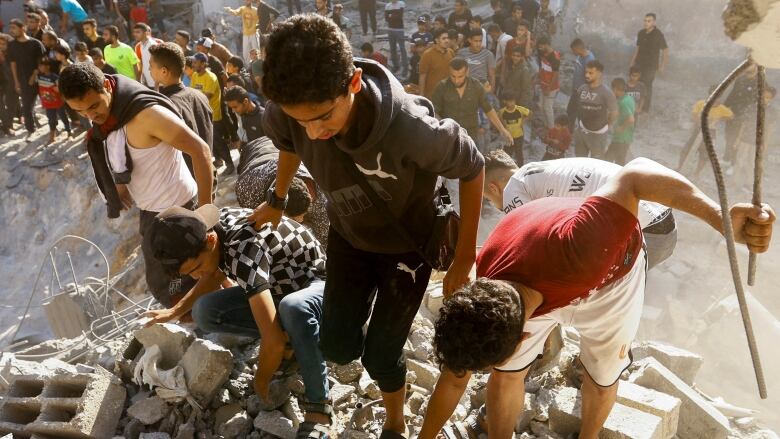 Three boys search through airstrike rubble in Khan Younis.