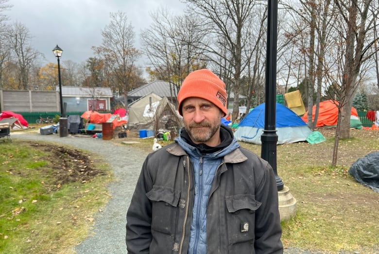 A man in an orange beanie looks friendly but serious.