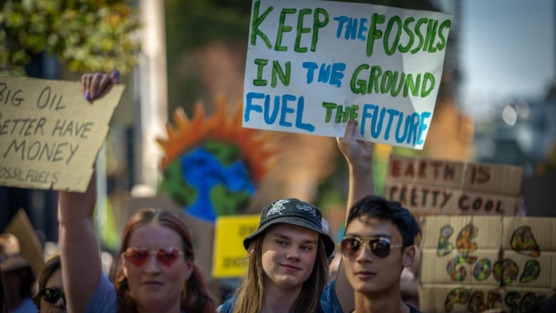 A girl holds up a sign that says keep fossil fuels in the ground.