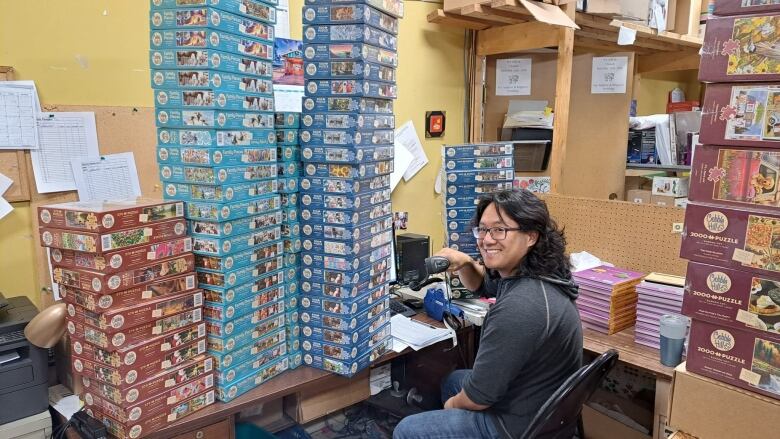 A man surrounded by boxes of puzzles.