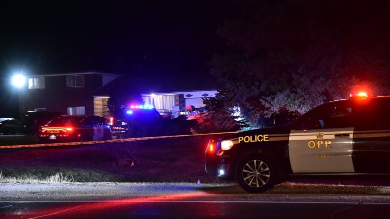 An OPP vehicle sits outside of a home surrounded by caution tape. 