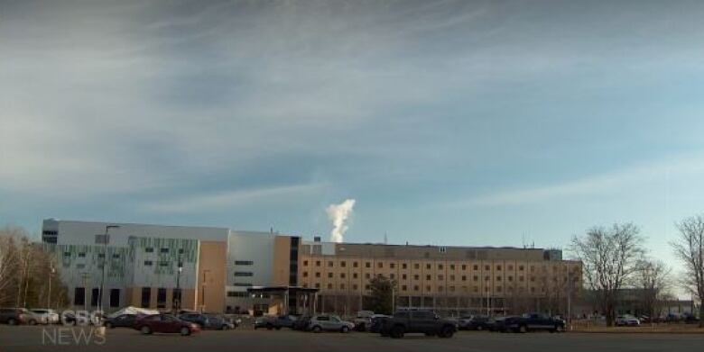 A brown brick building sits at the back of a parking lot.