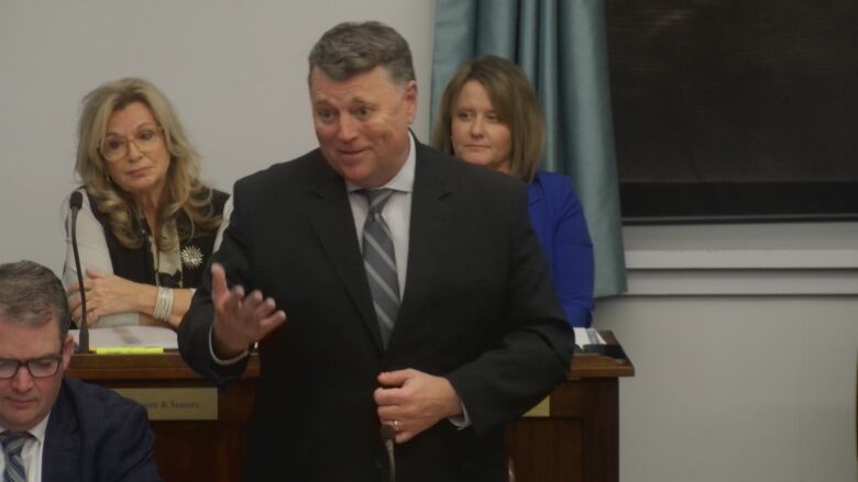 P.E.I. Premier Dennis King stands in a black suit while taking questions from fellow politicians.