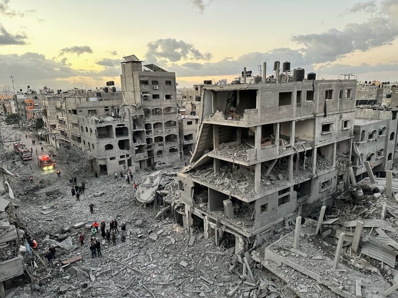 People are seen near destroyed buildings.